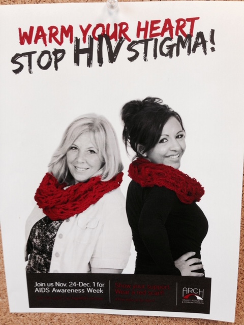 A poster for AIDS Awareness Week, sponsored by ARCH. The title reads, "Warm Your Heart, Stop HIV Stigma! Two women are shown on the poster who are wearing knitted red winter scarves that have been made by volunteers to raise public awareness and reduce the stigma felt by HIV/AIDS patients.