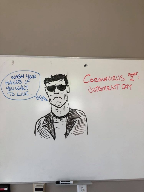 A sketch completed on a whiteboard. It reads on the right side in red: "Coronavirus Phase 2: Judgment Day." It features a figure with the likeness of Arnold Schwarzenegger with black sunglasses, a white shirt, and a black jacket. His face is frowning. He has short hair. There is a blue text bubble on the left side reading, "Wash your hands if you want to live." This sketch is a reference to the movie Terminator 2 while commenting on COVID terms like "phase 2" and guidelines like washing hands.